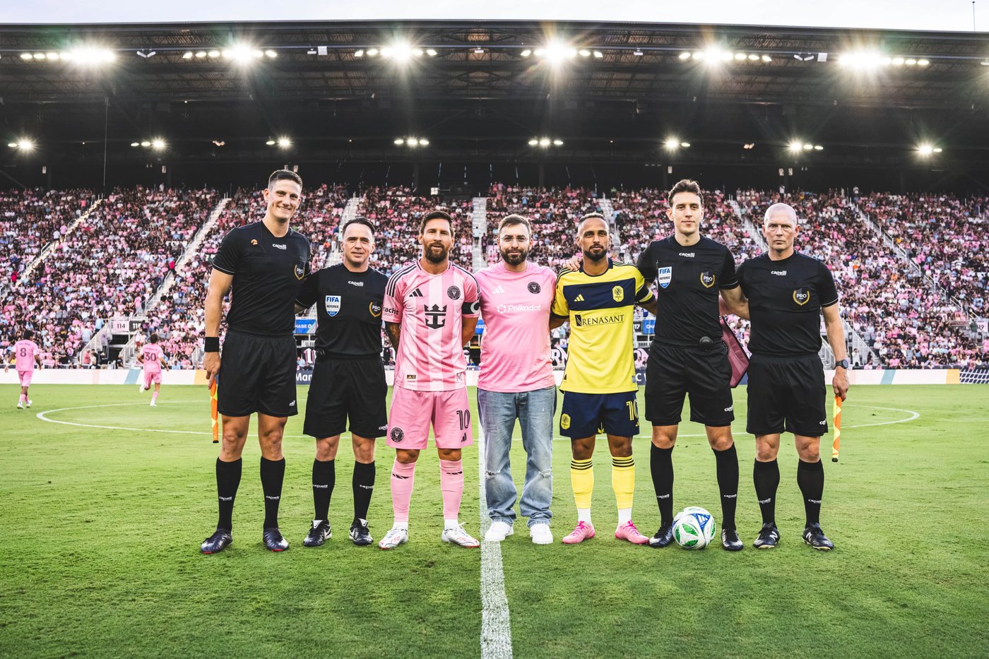 Sal Esposito at the centre circle for the coin toss with Lionel Messi, both captains and the match officials
